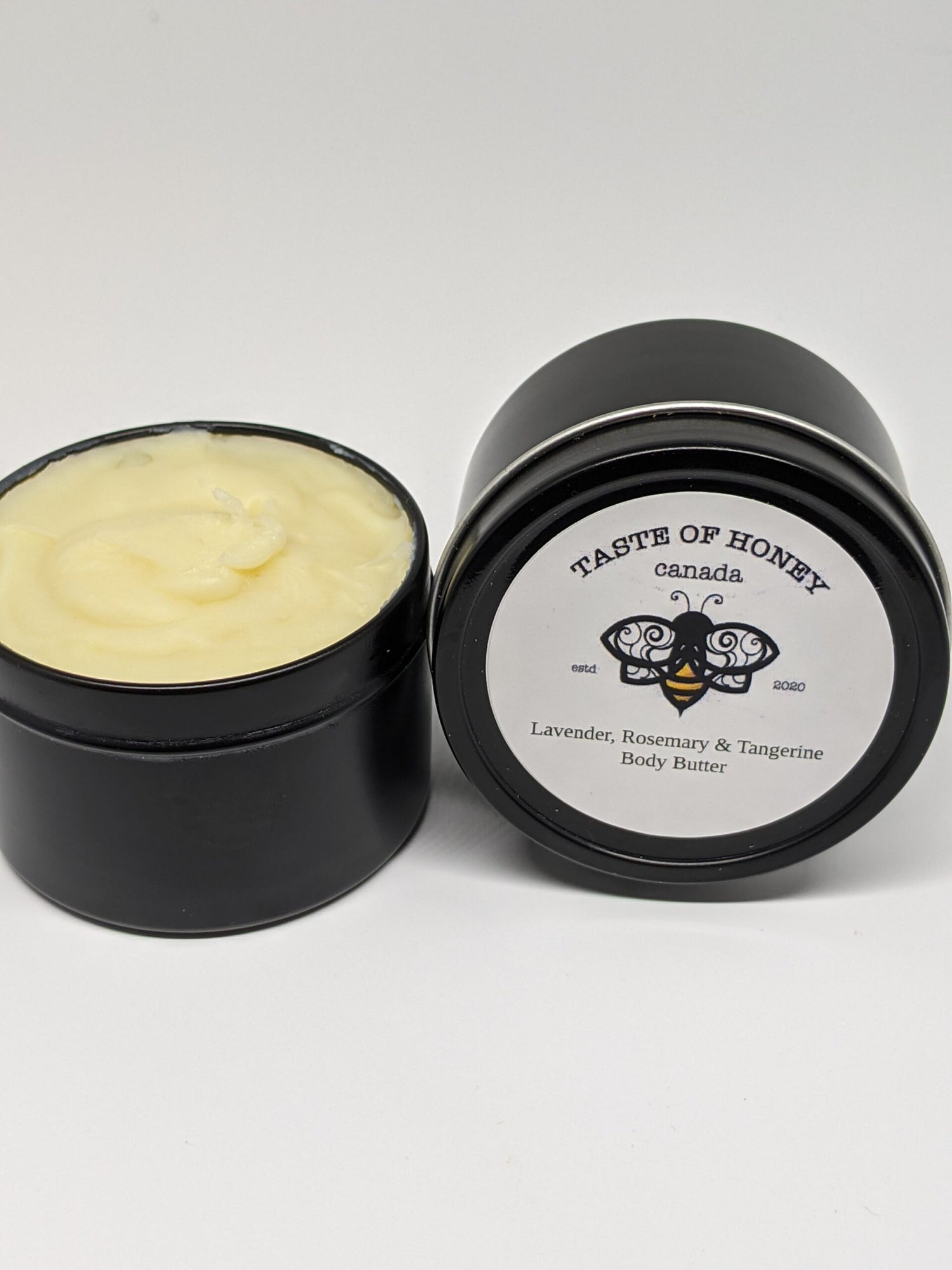 Lavender, Rosemary & Tangerine body butter.  Black tin, white label with bee logo.  Product color creamy yellow